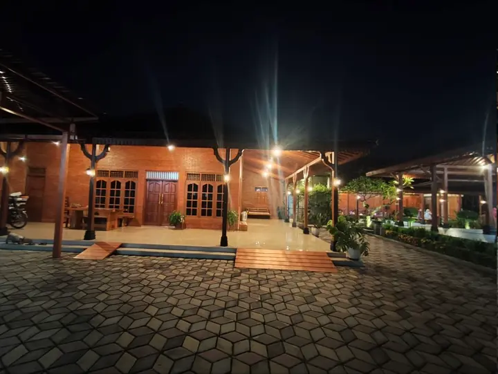 Fasad bangunan kayu dan teras yang hangat pada malam hari.
